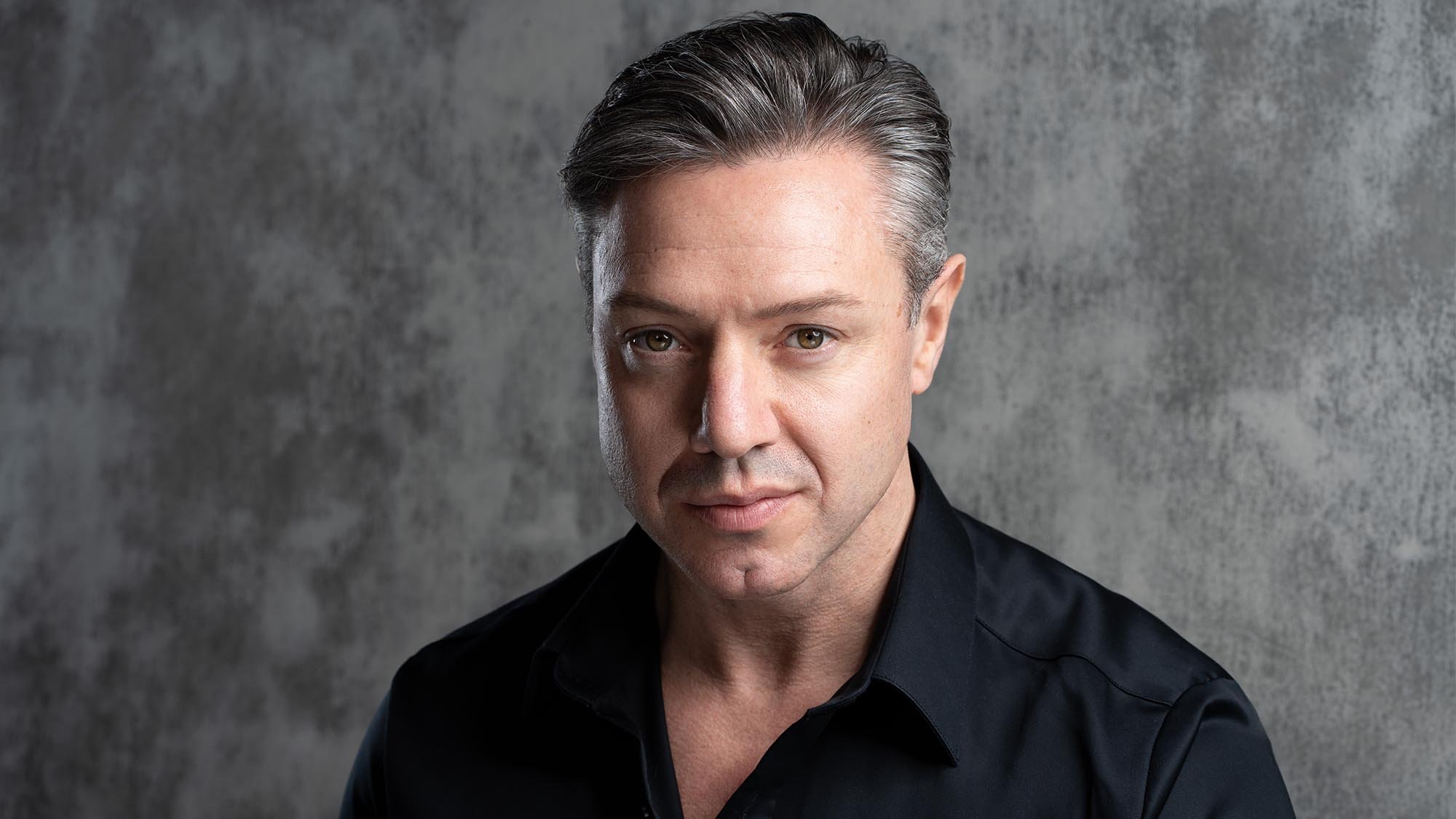 Headshot of a man wearing a black shirt.