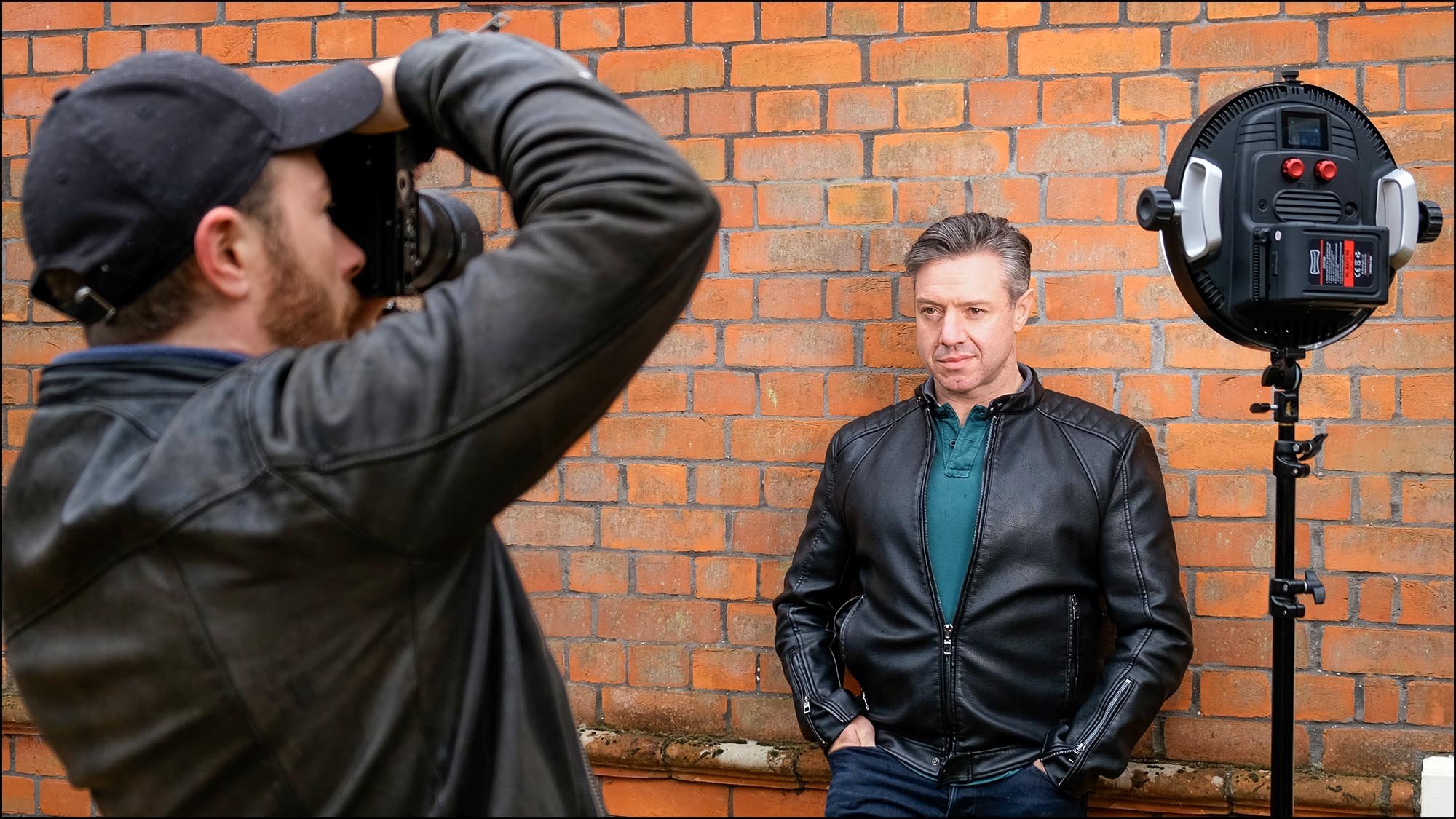 Photographer taking picture of man leaning on wall