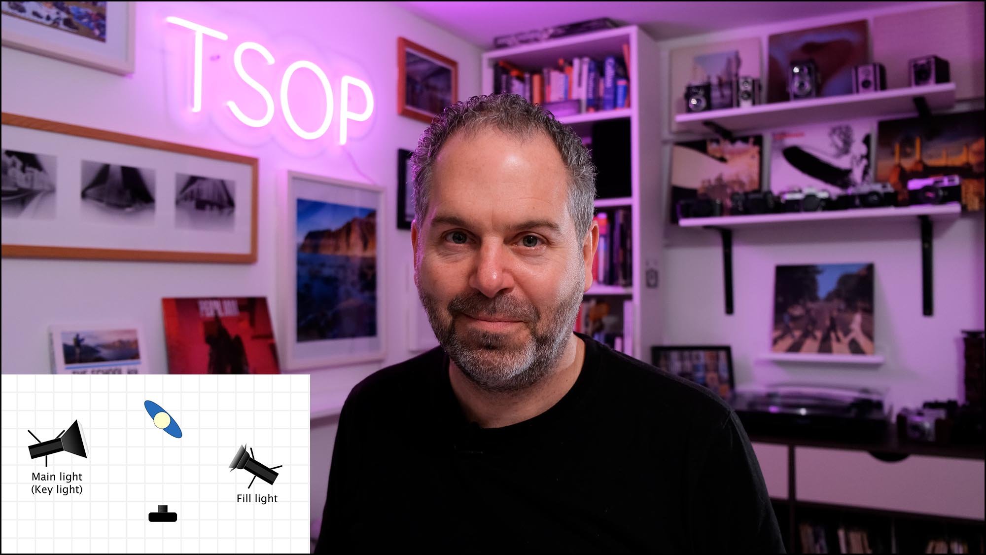 Photography instructor in a home studio with TSOP neon sign demonstrating key light and fill light setup for video recording